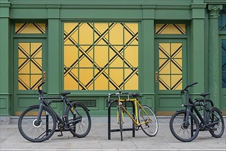 Three bicycles, green-yellow building facade
