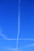 Two contrails form a plus in the blue sky,