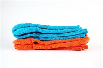 Self-knitted socks made of wool isolated against a white background in orange and blue,