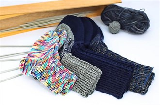 Self-knitted socks made of wool isolated against a white background. In different colours and sizes. With knitting needle and ball of wool,