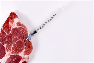 Concept for genetically modified animals or antibiotics and medicine residue in food with raw red meat with injected syringe,