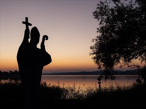 Silhouette of the stone statue of St. Pirmin after sunset, Reichenau Island