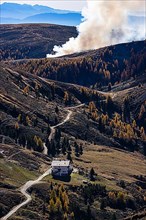 Rising smoke in autumnal landscape, in front the Merano Hut