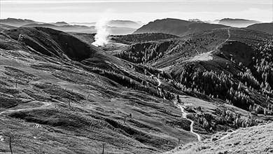 Rising smoke in mountainous landscape, black and white photo
