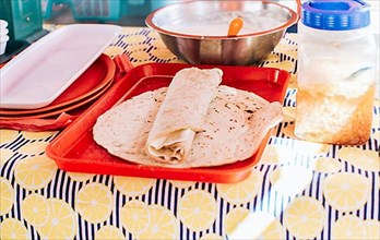 Nicaraguan quesillo made and served on the table. Traditional quesillo with pickled onion and wrapped tortilla. Traditional Nicaraguan Quesillo, food Traditional Large Quesillo served on table
