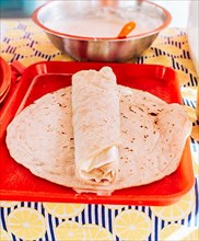 Food Traditional Large Quesillo served on table. Nicaraguan cheese made and served on the table. Traditional cheese with pickled onion and wrapped tortilla, Traditional Nicaraguan Quesillo
