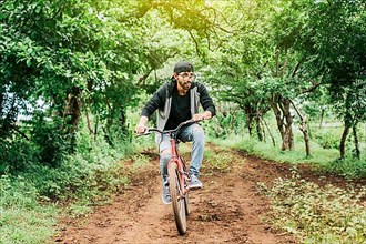 Teenage guy riding a bike in the countryside, Portrait of a guy in cap riding a bike on a country road
