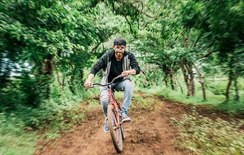 Portrait of a guy in cap riding a bike on a country road, Person riding a bike in the countryside