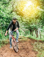 Person riding a bike in the countryside, Portrait of a guy in cap riding a bike on a country road