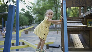 Cute little girl plays on the playground. Child girl playing on the playground in the city park. Odessa, Ukraine