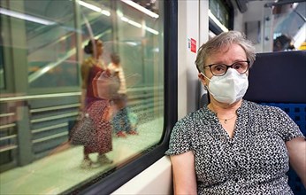 Older woman with mouth mask, sitting in S-Bahn