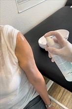 Patient's arm is disinfected by doctor's assistant with medical disinfectant spray Upper arm in front of injection for vaccination Booster against Covid-19 Corona virus Corona virus,