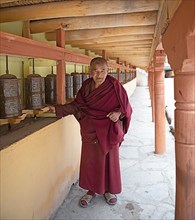 A monk with prayer wheels on a wall of Hemis Gompa, Hemis