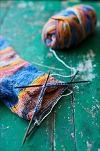Handwork, knitted sock with knitting needles and wool