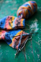 Handwork, knitted sock with knitting needles and wool