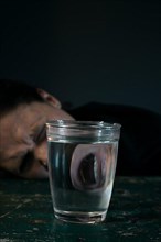 Pain-distorted face of a woman reflected in a glass of water,
