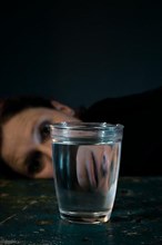 Face of a woman reflected in a glass of water,