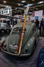 Historic vintage Volkswagen VW Beetle with pretzel window, skis and ski poles lashed to the back of the bonnet