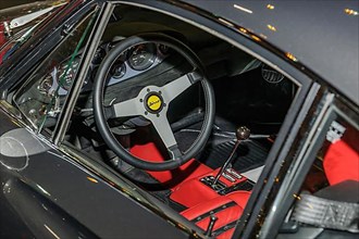View into interior of Ferrari Dino from 60s 70s with steering wheel and lever of manual gear shift, fair Techno Classica