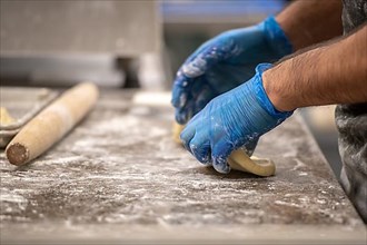Man's hands in protective gloves rolls out dough, Baltimore
