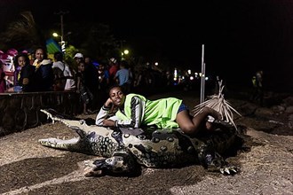 Woman lying on papier mache crocodile, dummy