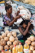 Two woman braiding hair, market stall