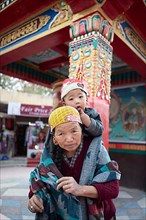 Ladakhi woman carrying her grandson on her shoulders, Leh