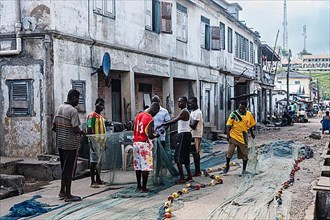 Fishermen mending nets, Elmina