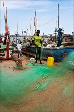 Fishermen mending nets, fishing boats