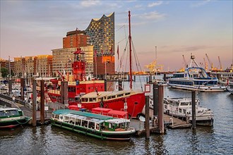 Museum lightship and launches in front of the Elbe Philharmonic Hall on the Elbe in Hamburg harbour in the evening sun, Hamburg