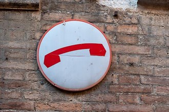 Red telephone receiver, sign on house wall