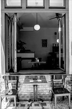 Black and white, view through the open window into a bistro