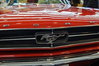 Bonnet of historic classic sports car classic car Ford Mustang with radiator grille and emblem of horse, fair Techno Classica
