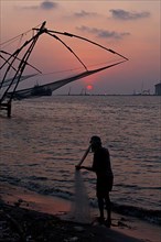 Fisherman and Kochi chinese fishnets on sunset. Fort Kochin