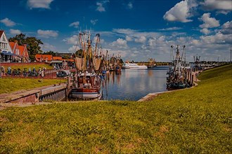 The fishing harbour in Greetsiel in sunshine and a few spring clouds in the blue sky