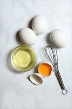 Egg whites in small bowls and egg yolks in egg shells