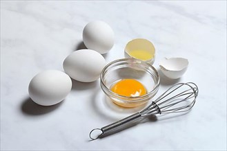 Egg yolks in small bowls and egg whites in egg shells