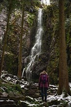 Woman in front of waterfall in winter landscape
