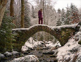 Woman in red standing on icy bridge in winter landscape