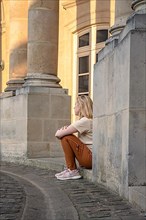 Woman sitting on the edge of a historic building in downtown Paris