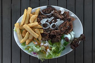 Giros with fries and salad with tzatziki served in a Greek restaurant