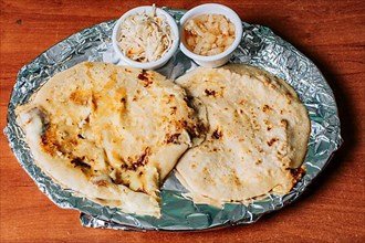 Top view of two Nicaraguan pupusas served with salad on the table. Delicious Salvadoran pupusas with melted cheese served on the table. Traditional pupusas served with salad on the table