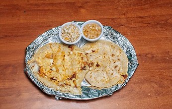 Two Nicaraguan pupusas served with salad on the table. Delicious Salvadoran pupusas with melted cheese served on the table. Traditional pupusas served with salad on the table