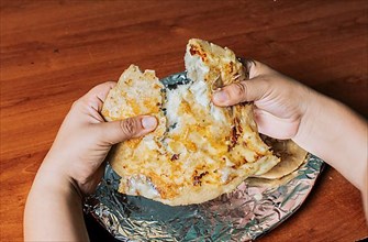 Hands dividing delicious Nicaraguan pupusa on the table