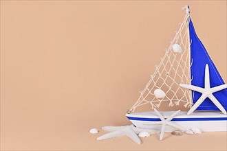 Small sailing boat decoration with starfish and seashells and copy space