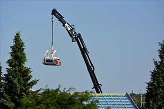 Truck-mounted crane on the roof of the house with new tiles