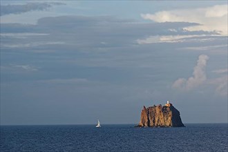 Sailboat in front of the small island of Eolie with lighthouse