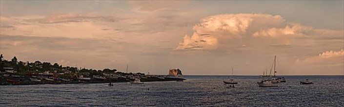 Small fishing village and harbour of San Vincenzo island and Stromboli volcano at sunset and anchored sailboats