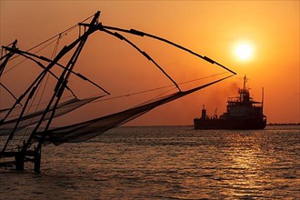 Kochi chinese fishnets on sunset and modern ship. Fort Kochin