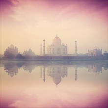 Vintage retro hipster style image of Taj Mahal on sunrise sunset reflection in Yamuna river panorama in fog